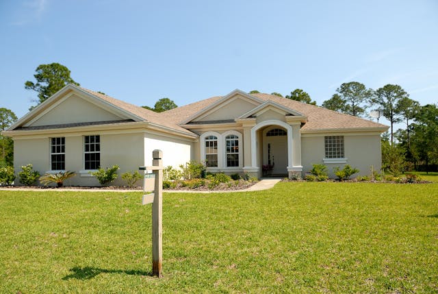 A large house with a sign in the front lawn.