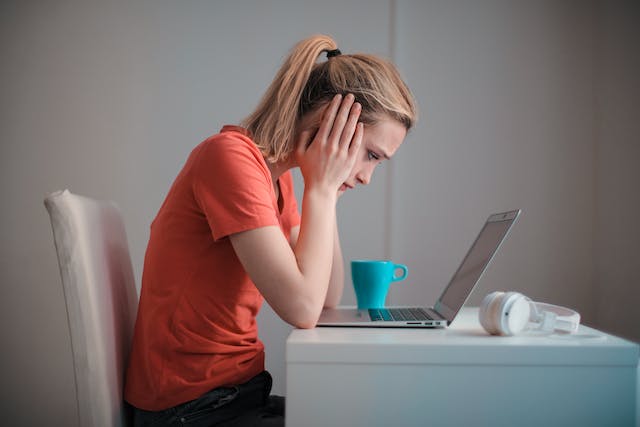 A person looking stressed at a laptop.